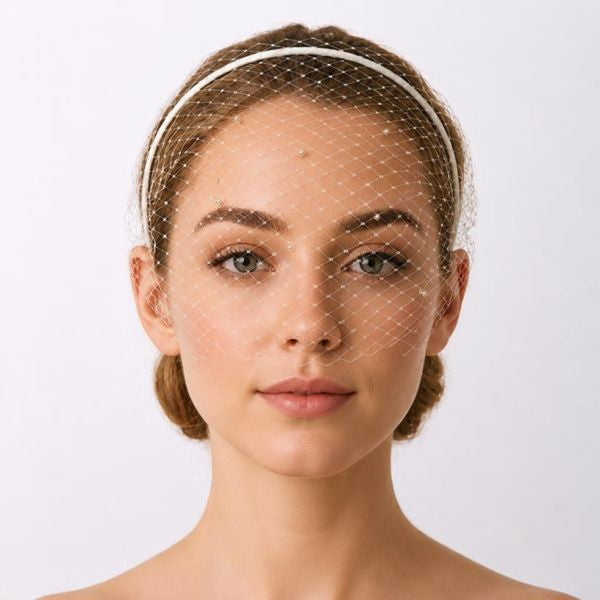 model wearing an ivory birdcage bridal veil with a thin headband.
