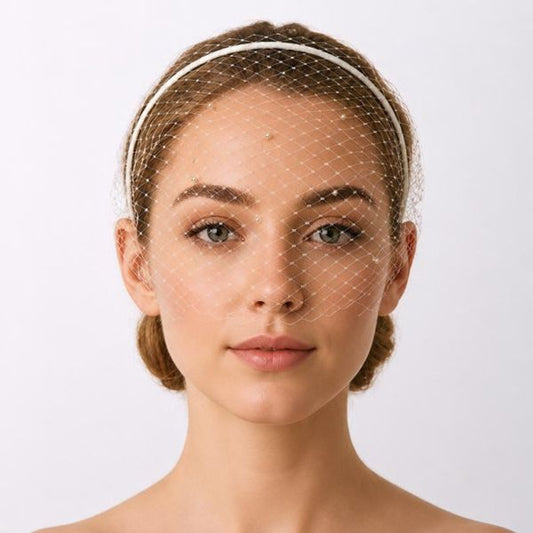 model wearing an ivory birdcage bridal veil with a thin headband.