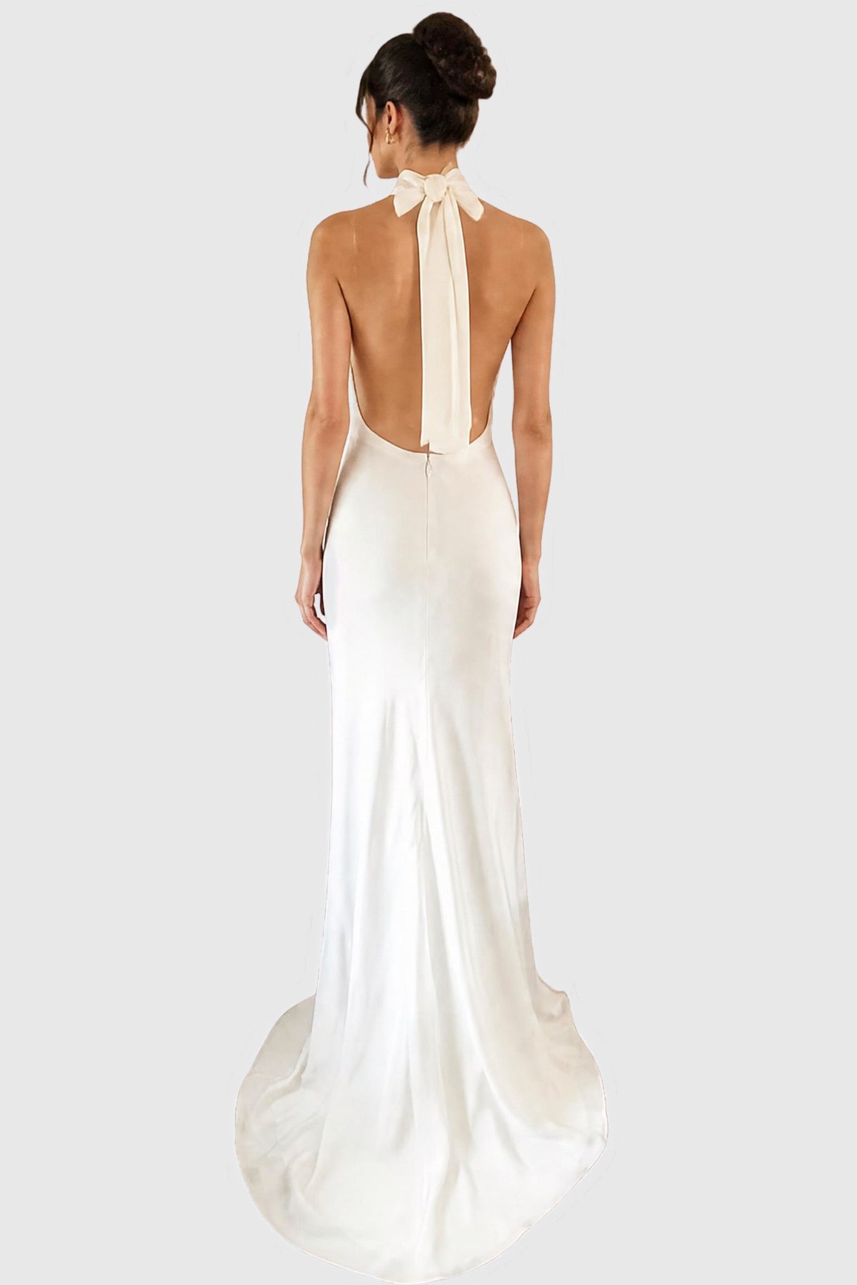 A woman shown from the back wearing a floor-length light ivory bridal gown with a high neck, bow detail at the back of the neck, and a slight train.