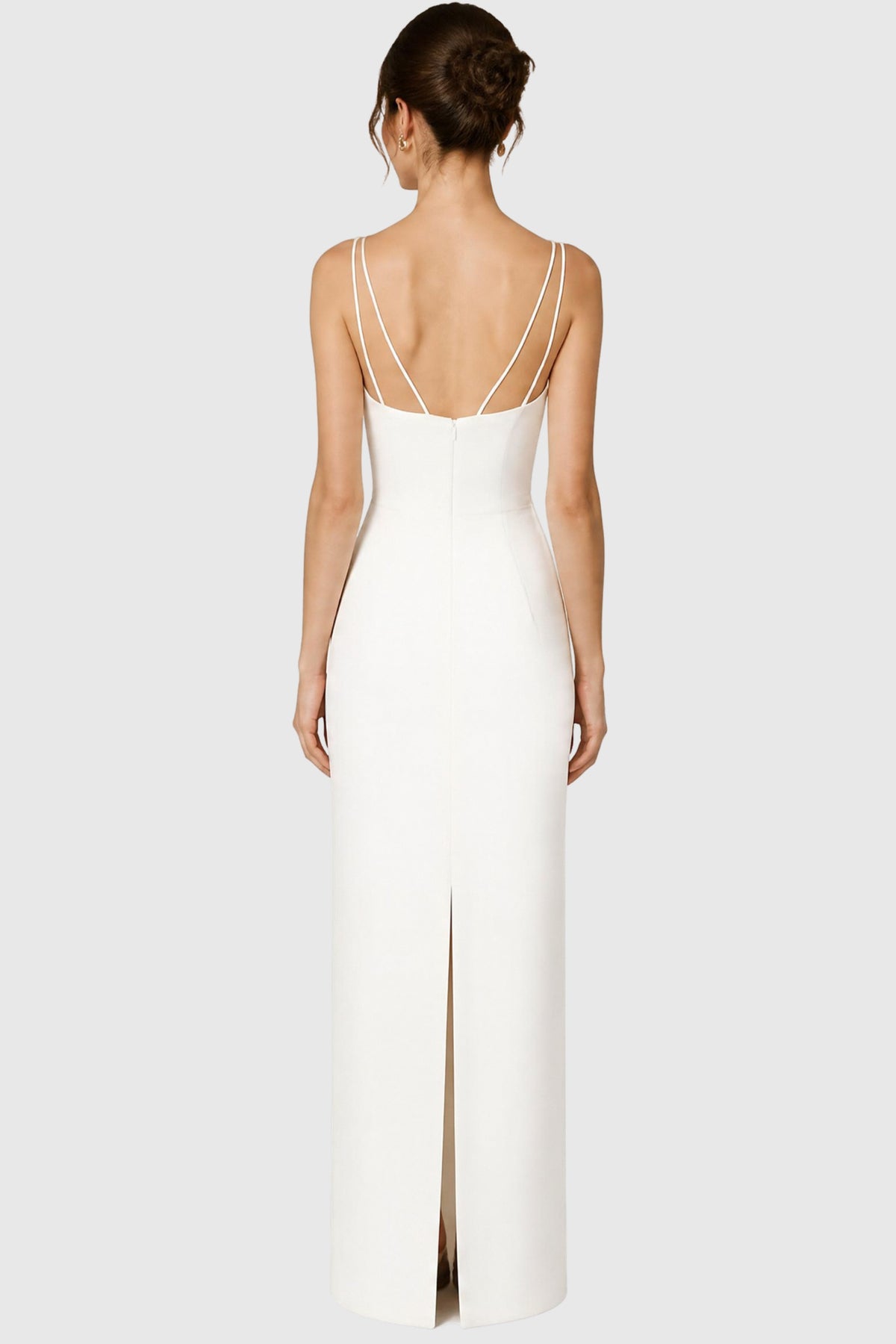 A model shown from the back wearing a light ivory column wedding dress with double shoulder spaghetti straps and a back slit.